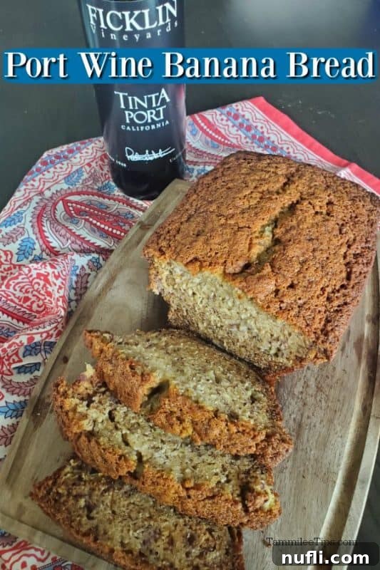 A golden-brown loaf of Tinta Port Wine Banana Bread rests on a wooden cutting board, with a bottle of Ficklin Vineyards Tinta Port in the background, suggesting a delightful culinary pairing.