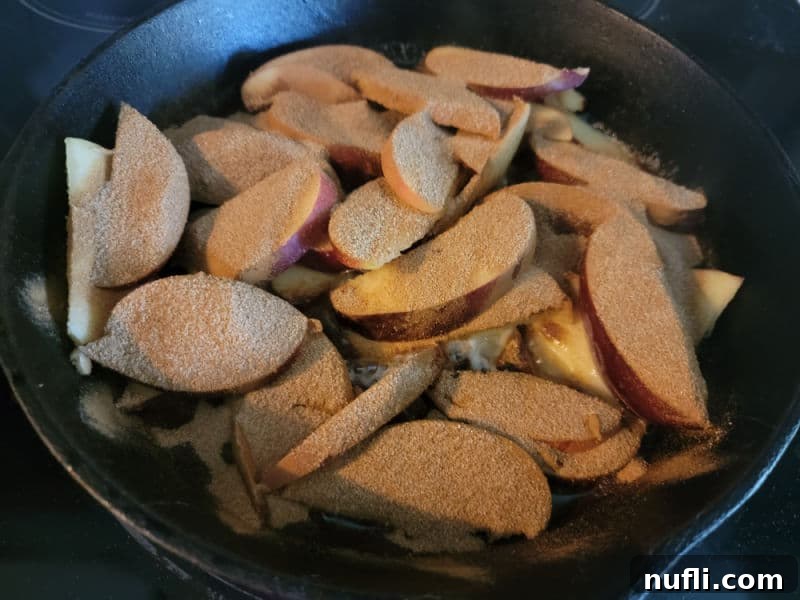 Easy German Apple Pancakes 5 Sliced apples covered in cinnamon for a German Apple Pancake in a cast iron skillet