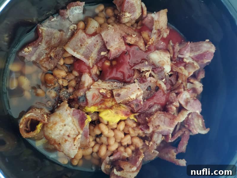 Bourbon baked beans ingredients piled together in a slow cooker before stirring