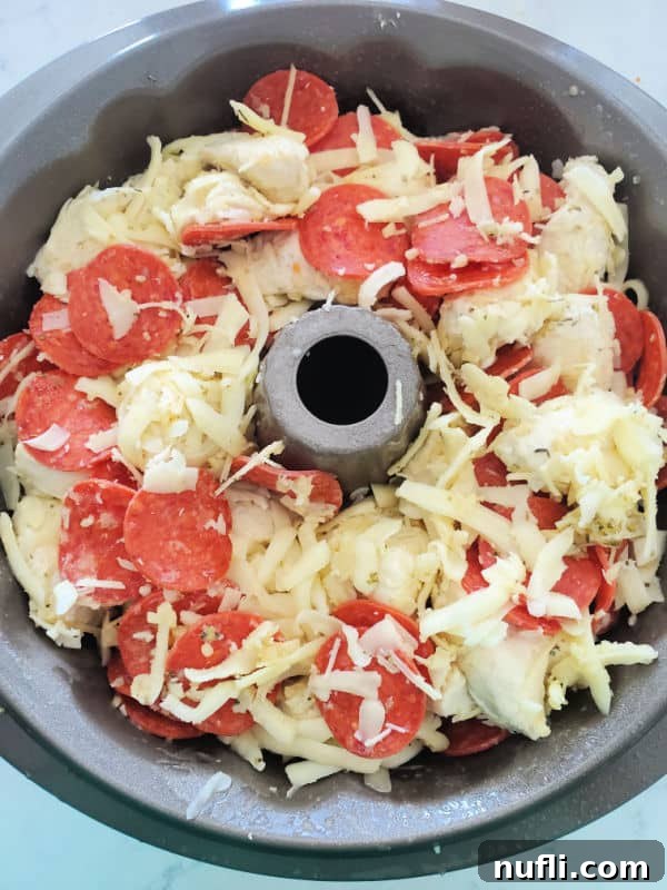 Unbaked Pepperoni Pizza Monkey Bread mixture in a Bundt pan, ready for the oven