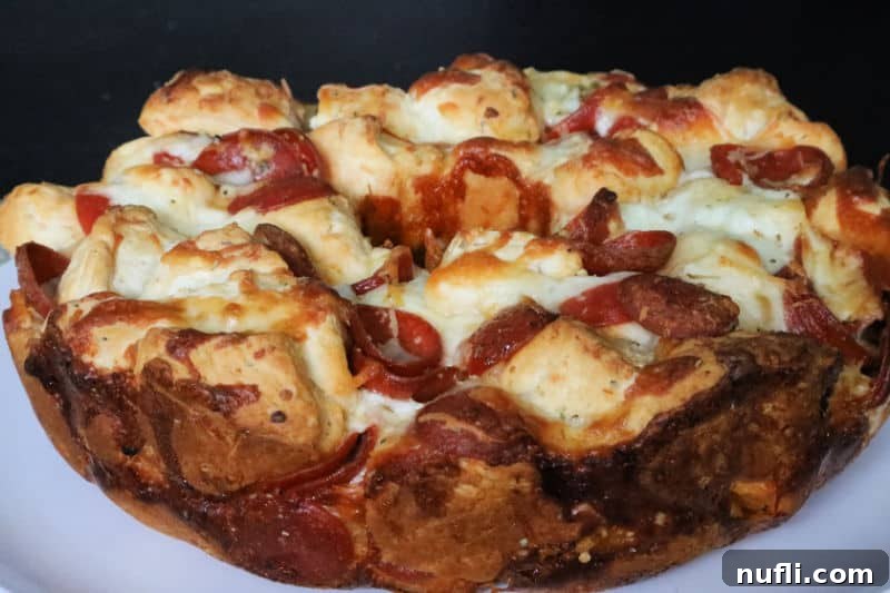 Close up of a slice of Pepperoni Pizza Monkey Bread, highlighting the gooey cheese and pepperoni pieces