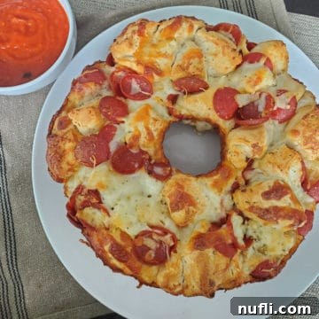 Pepperoni Pizza Monkey Bread on a white plate next to a bowl of marinara