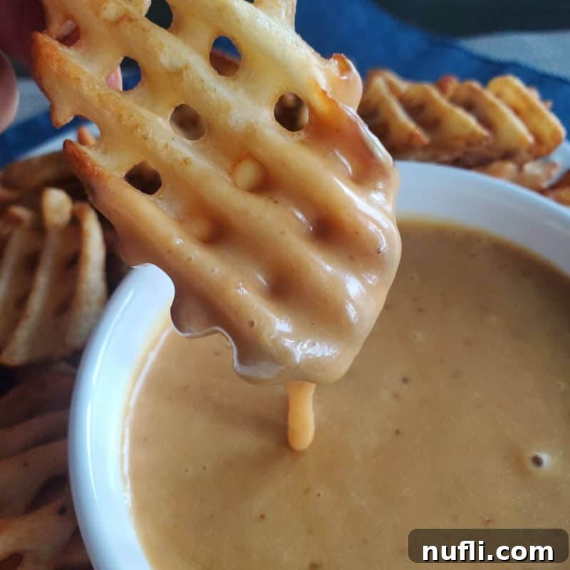 Waffle fry dipping into Chick-fil-A sauce in a white bowl