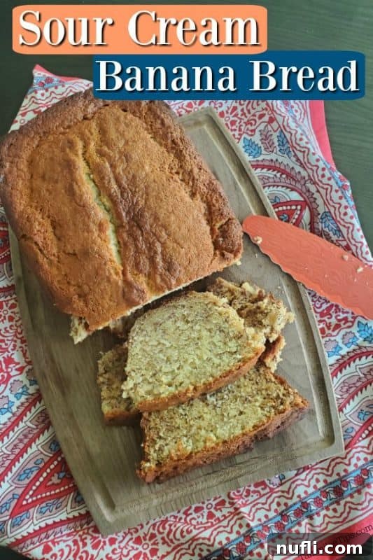 A golden-brown loaf of sour cream banana bread resting on a wooden cutting board, with several perfect slices cut and a serrated knife leaning nearby, showcasing its soft interior.