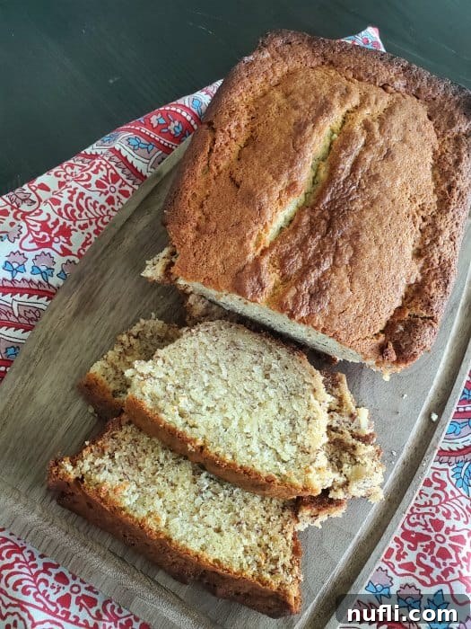 Two generous slices of moist sour cream banana bread beautifully displayed on a wooden cutting board, ready for enjoyment.