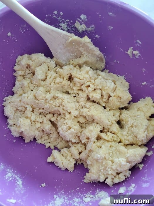 Lemon Cheesecake Bars Video Recipe 4 dough crumble in a purple bowl with a wooden spoon