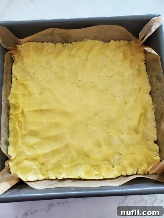 Lemon Cheesecake Bars Video Recipe 5 dough pressed into a parchment lined baking sheet.