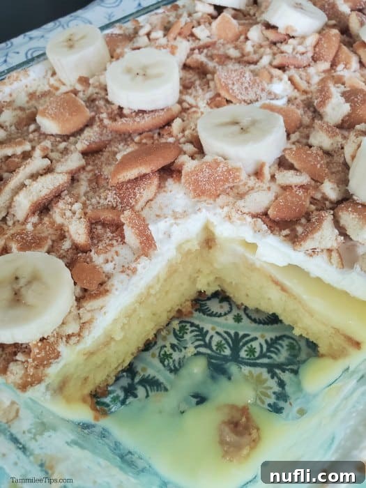 Ultimate Banana Pudding Poke Cake 4 A prepared Banana Pudding Poke Cake in a baking dish, with one square slice removed, revealing the delicious layers of cake and pudding.