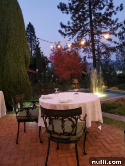 Romantic table for two under lights with a lighted fountain near it