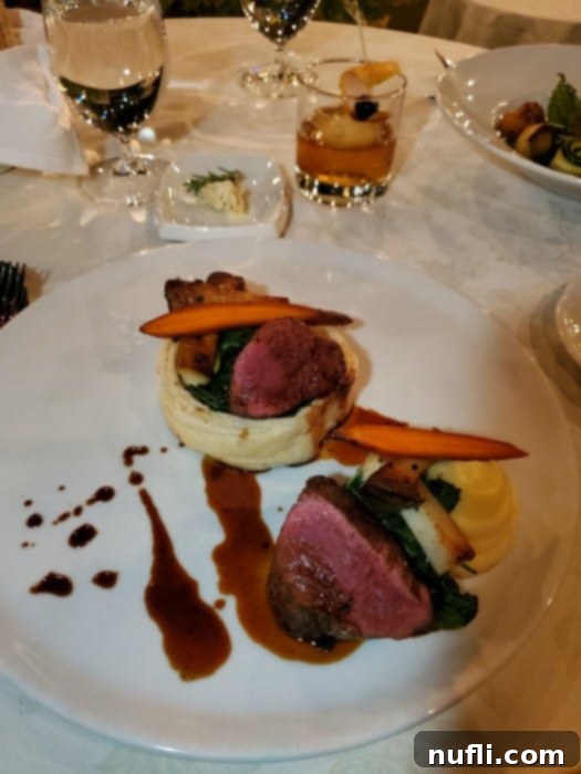 filet mignon with potatoes on a white plate next to a cocktail and glass of water and Erna's Elderberry 