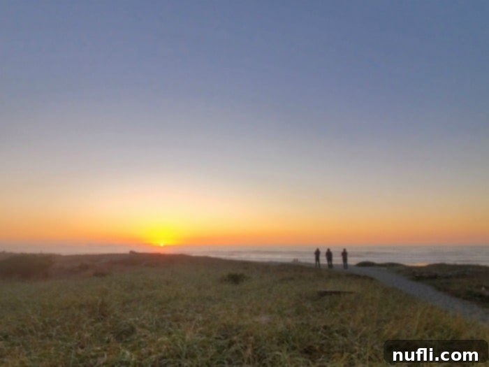 People in the distance on a trail looking out at sunset over the Pacific ocean 