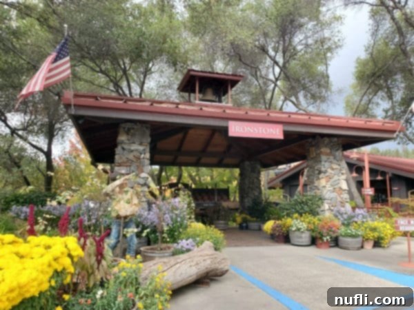 Ironstone winery sign over the entrance to the winery with buckets of flowers and plants