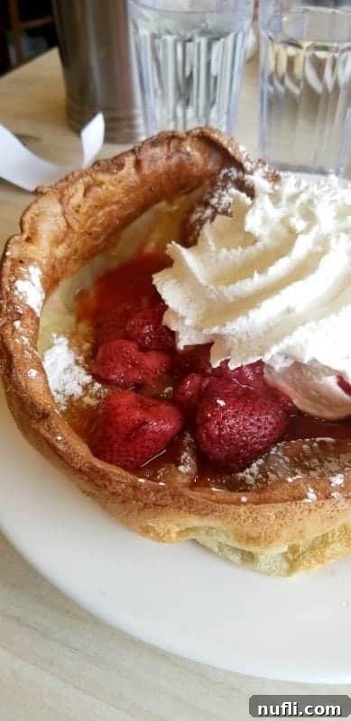 dutch baby with whipped cream and strawberries on a white plate