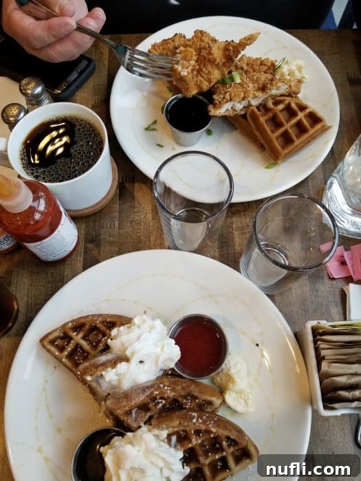 A table with two plates of waffles, glasses, and coffee