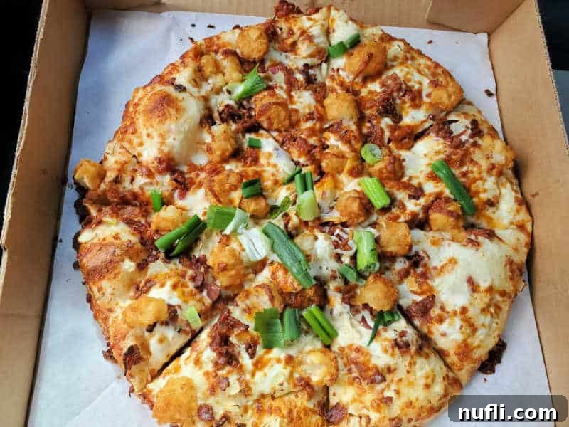 Spokane's Top Pizza Spots 24 tater tot, green onion, and cheese on a pizza in a cardboard delivery box