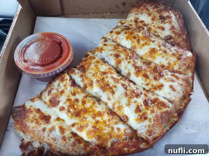 Spokane's Top Pizza Spots 25 cheese bread next to a container of red sauce in a delivery box