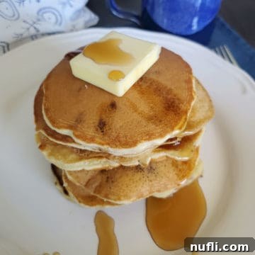The 3 Ingredient Muffin Mix Pancake Hack 7 A stack of delicious Muffin Mix Pancakes, generously topped with melting butter and dripping maple syrup, ready to be served.