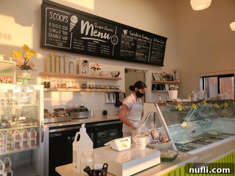 Scoops menu above the ice cream counter with a person standing next to the counter