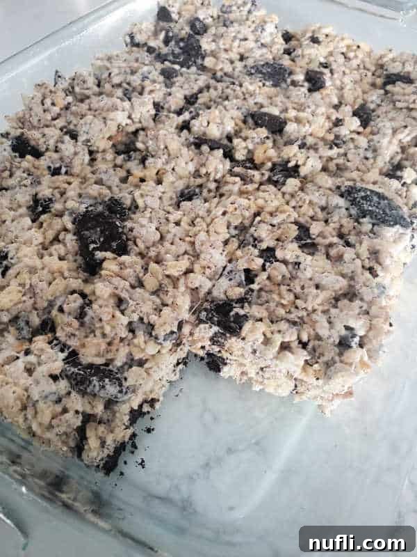 Oreo Rice Krispies in a glass baking dish with one square missing.