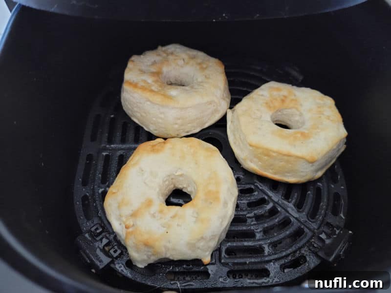 Three air fryer biscuit donuts in an air fryer basket