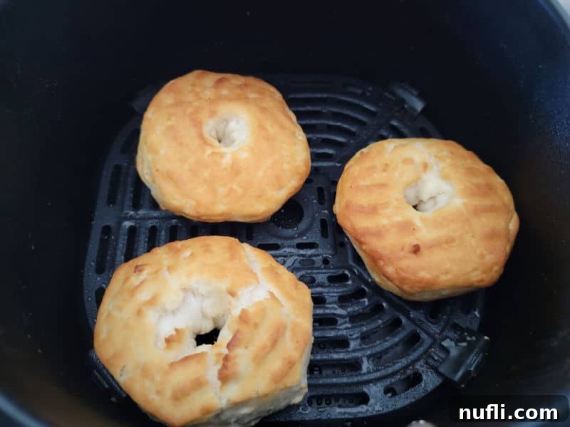Three air fryer donuts on a greased air fryer basket. 