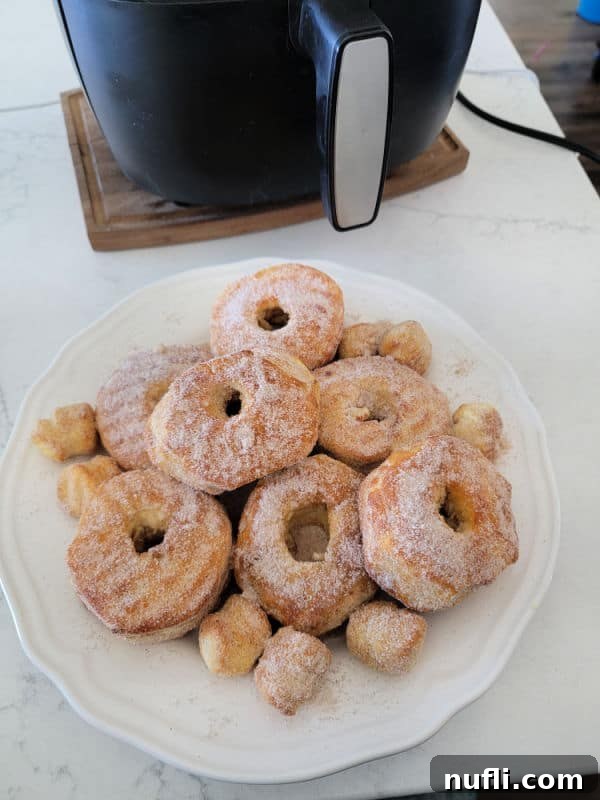 White plate filled with air fryer doughnuts with air fryer in the background.