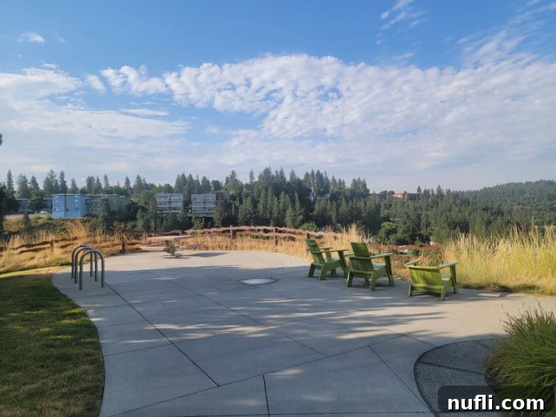 Green adirondack chairs lined up on an overlook of the Spokane River with buildings in the distance