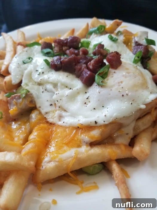 Breakfast poutine on a plate topped with bacon