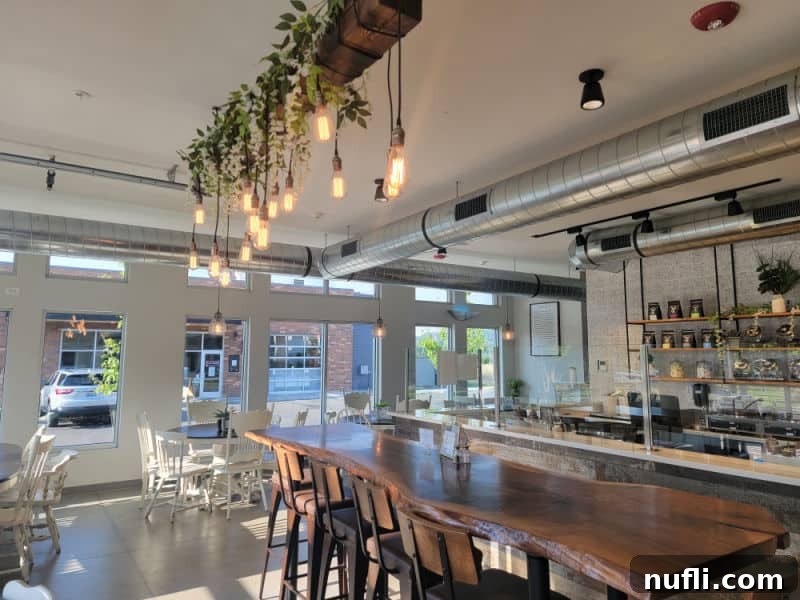 long wooden table in the middle of a brightly lit restaurant with a un chandelier overhead