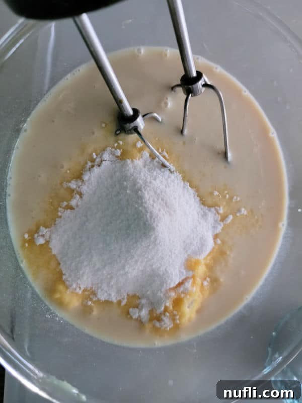 Pudding mixture ingredients being combined in a bowl with a hand mixer.