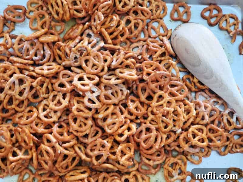 Freshly baked ranch pretzels spread out on a baking dish with a wooden spoon, cooling down.