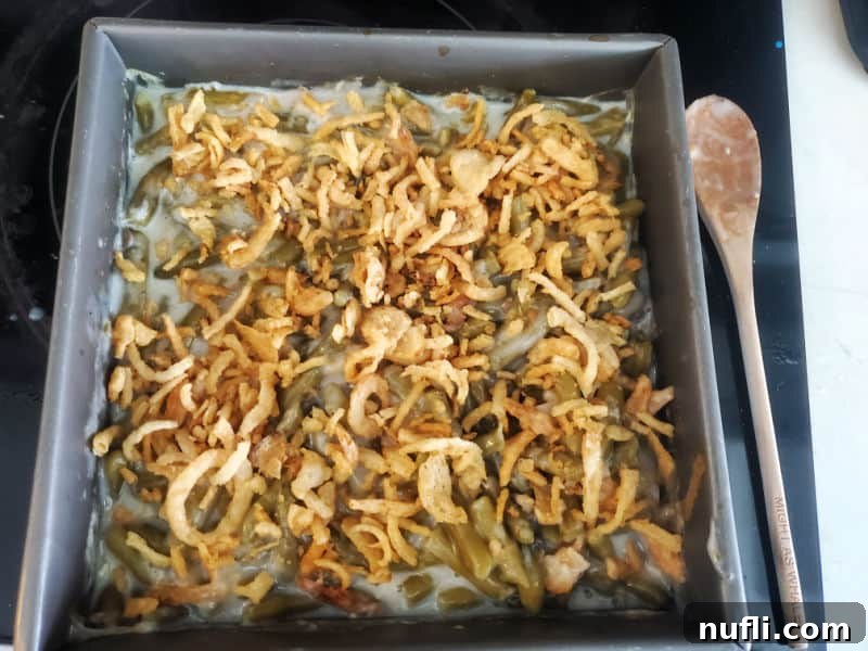 Campbell's Green Bean Casserole baking dish with a wooden spoon next to it