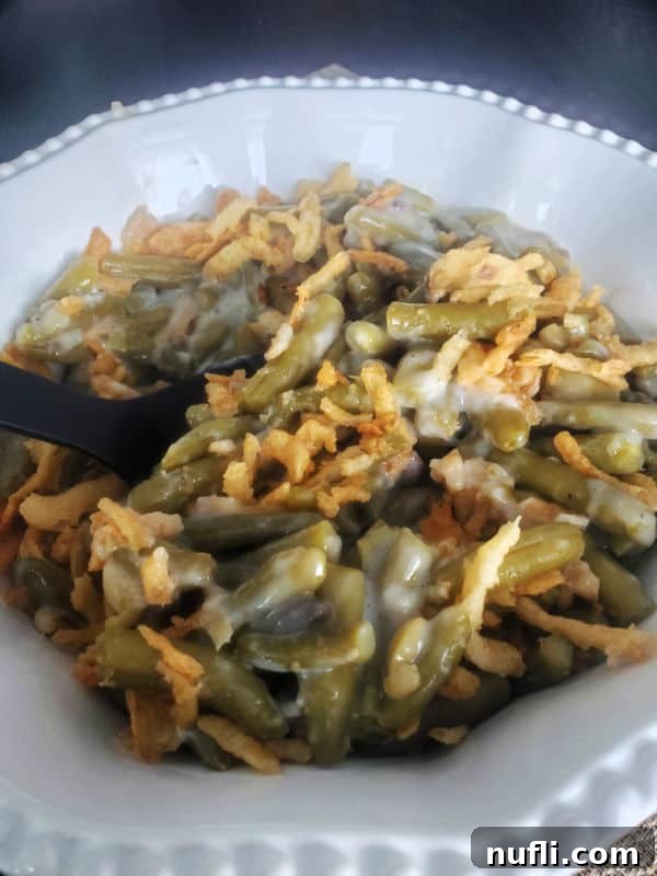 Campbell's Green Bean Casserole in a white serving bowl with a black spoon, ready to be served