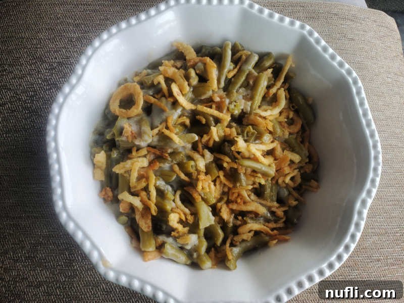 Campbell's Green Bean Casserole in a white serving bowl on a brown placemat, ready to be enjoyed