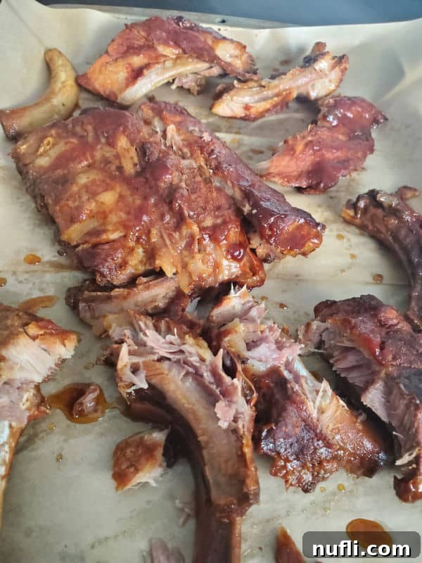 Tender, saucy Dr. Pepper ribs arranged neatly on a parchment-lined baking sheet, ready for serving or a final broil.