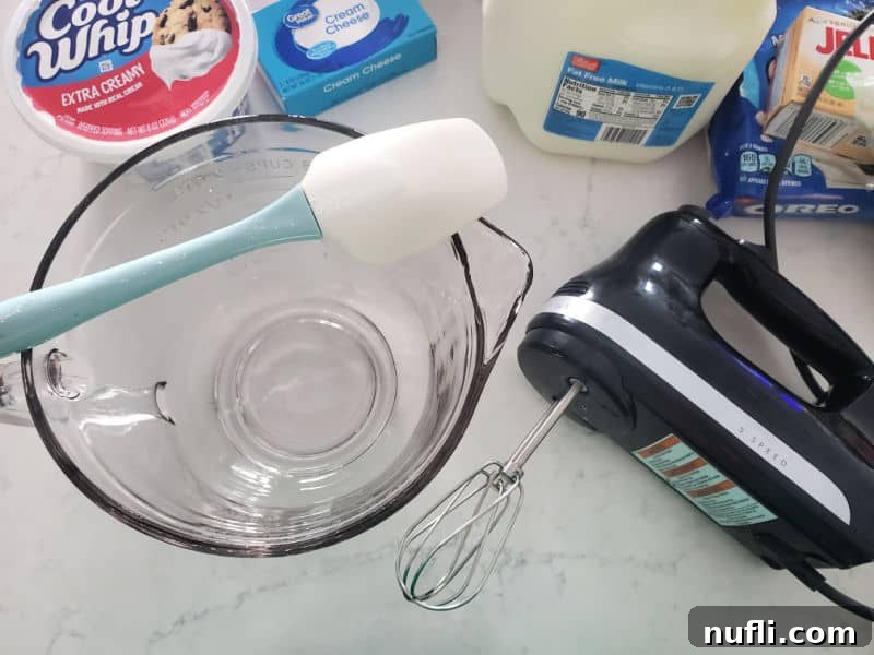 Glass bowl, spatula, hand mixer, cool whip, cream cheese, milk and jello for Oreo Fluff