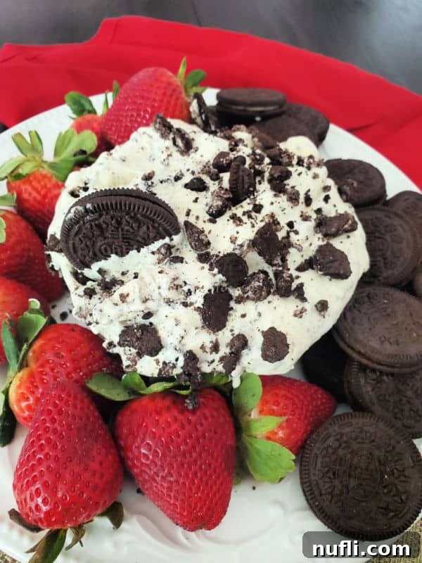 Oreo cookie salad in a bowl next to strawberries and Oreo Cookies with a red napkin