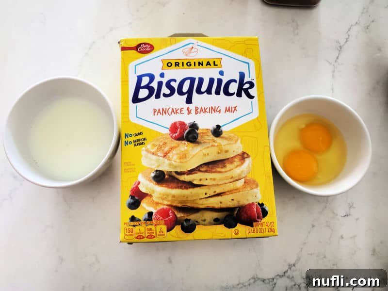 A selection of raw ingredients for pancake muffins laid out on a kitchen counter: a bag of Bisquick mix, several fresh eggs, and a glass of milk.
