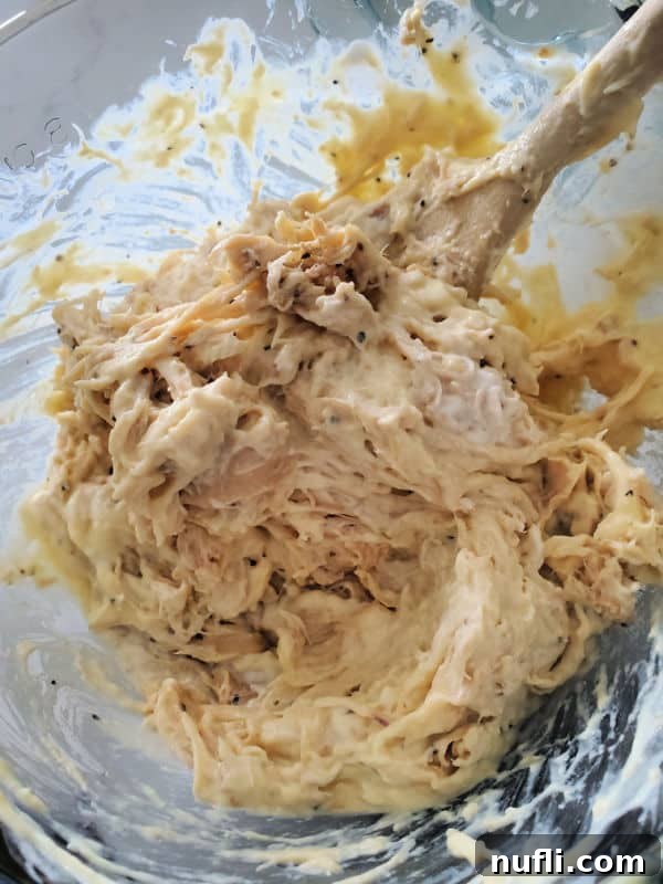 Golden Ritz Topped Chicken Casserole 4 shredded chicken sour cream mixture in a glass bowl with a wooden spoon