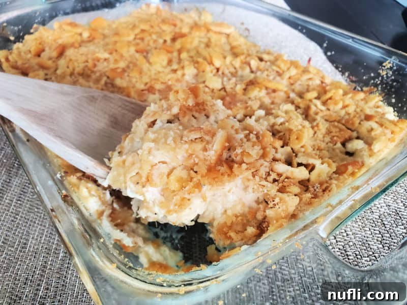 Golden Ritz Topped Chicken Casserole 8 wooden spoon scooping ritz chicken casserole out of a baking dish