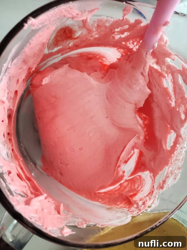 Kool Aid Pie pink mixture in a glass bowl with a spatula