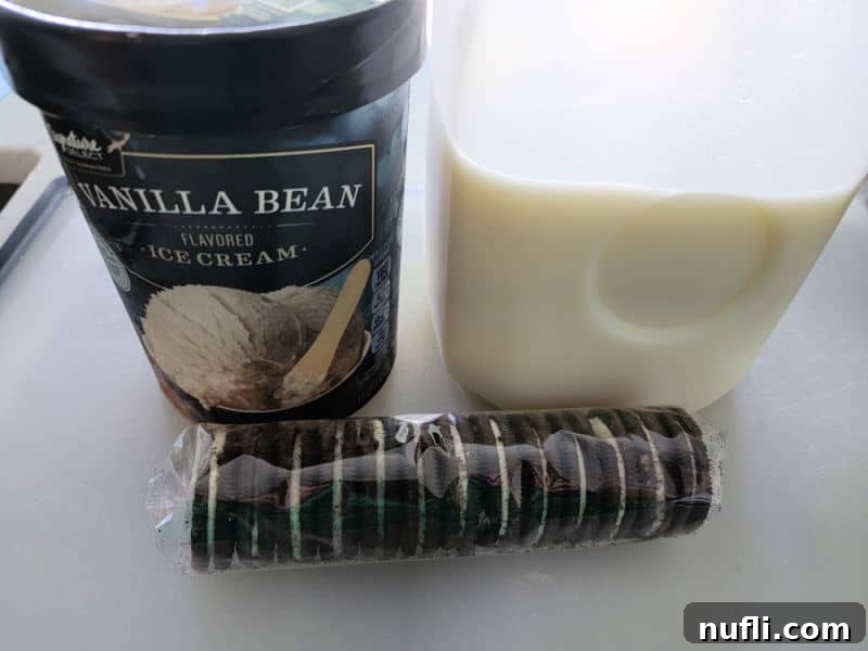 Oreo Milkshake ingredients displayed: vanilla ice cream, a glass of milk, and a stack of Oreo cookies, ready for blending into a delicious treat.