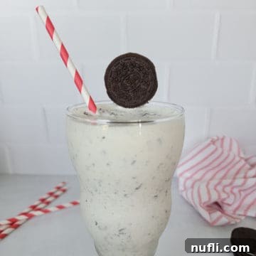 Delicious Oreo Milkshake Recipe in a shake glass with a red striped straw, ready to be enjoyed.
