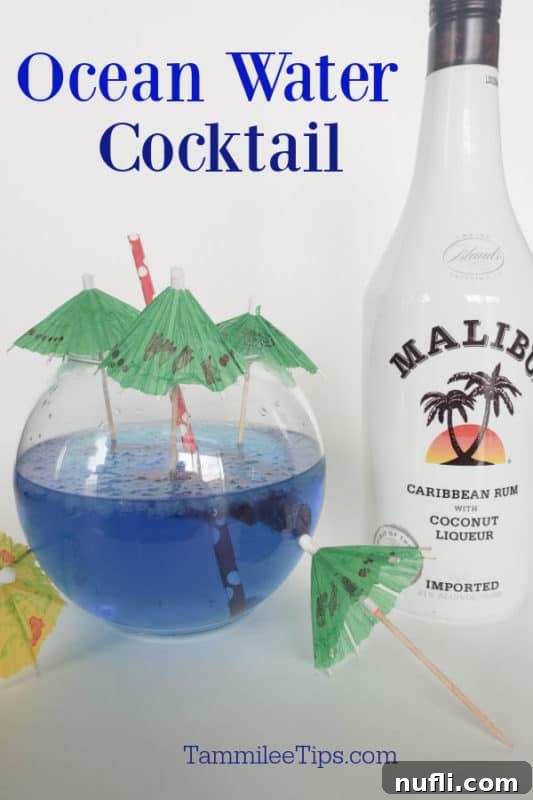 Homemade Sonic Ocean Water Drink Guide 4 A fishbowl glass filled with blue Sonic Ocean Water, with a bottle of Malibu Coconut Rum in the background, signaling an adult cocktail version.