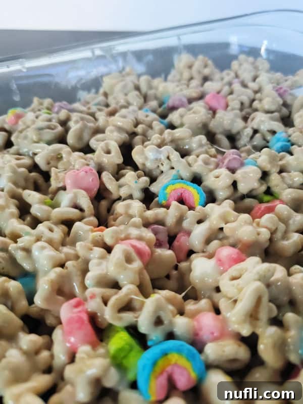 Lucky Charms treats freshly pressed into a glass baking dish, ready to cool.