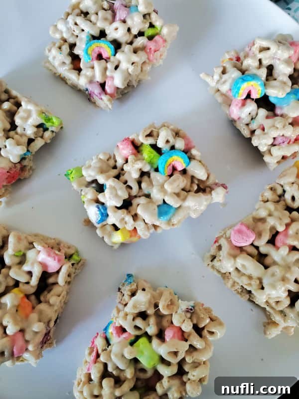 Individual square Lucky Charms treats artfully spread on a white plate, showcasing their vibrant colors.