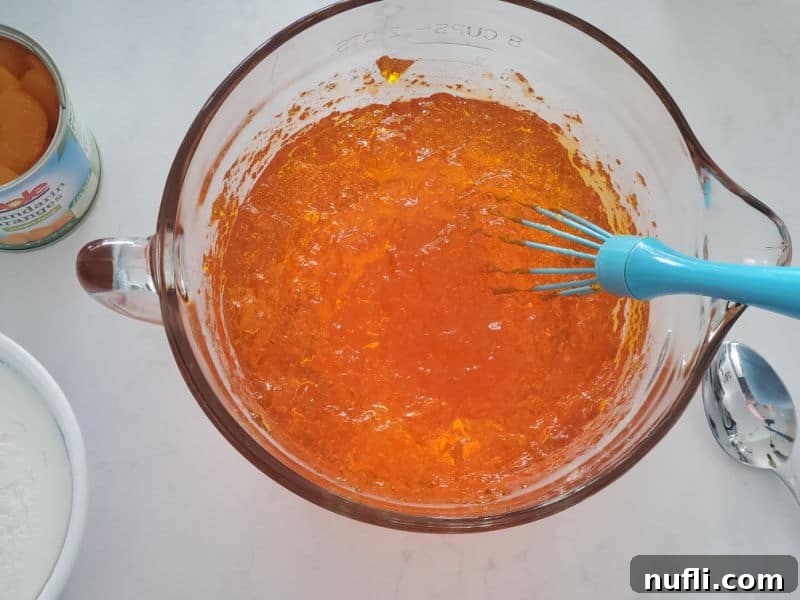clear mixing bowl with a blue whisk and jello mix