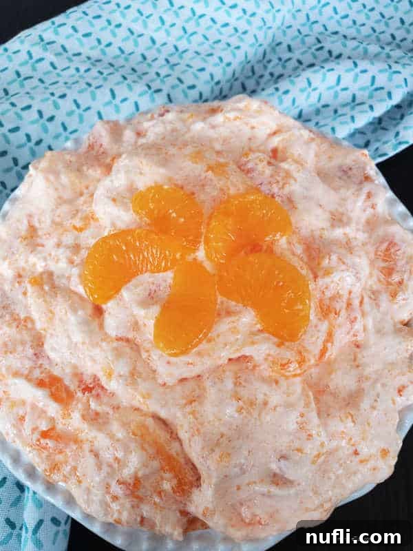 Mandarin Orange Jello Salad in a white bowl next to a cotton towel 