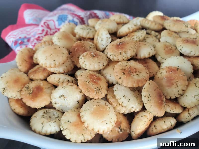 A crisp, white bowl generously filled with homemade dill oyster crackers, showcasing their golden-brown color and seasoning.