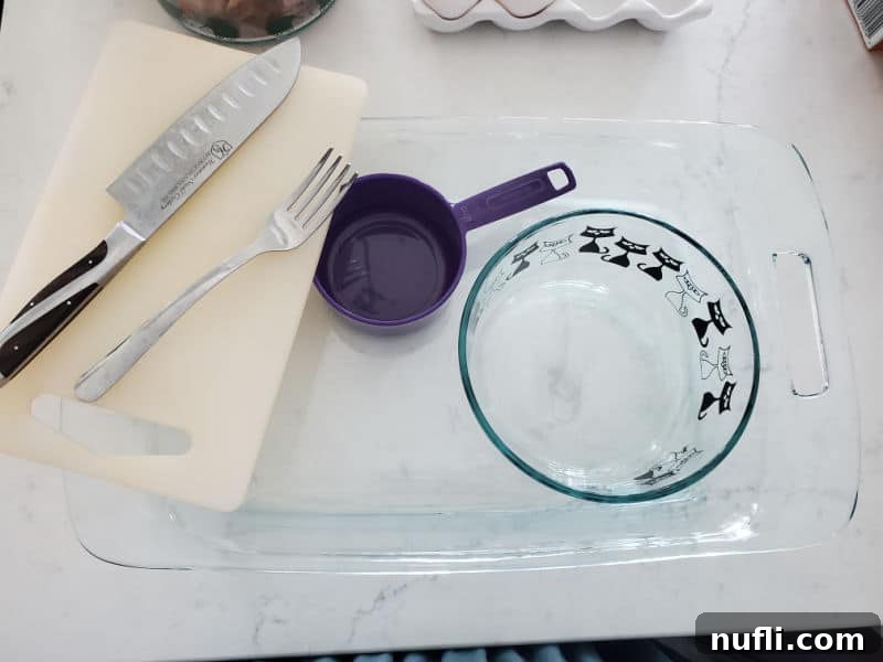 Knife, fork, cutting board, measuring cup, glass bowl, and glass baking dish on a counter. 